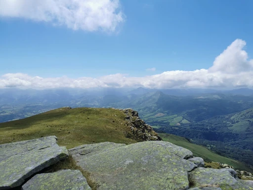 Rock slabs on a ridge in the Basque hills near Ascain, with green valleys falling away below. The massif of La Rhune, shown without the train.
