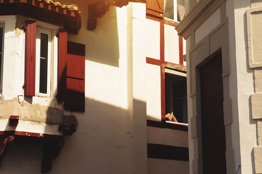 Sunlit white Basque house fronts with red wooden shutters in Saint-Jean-de-Luz.