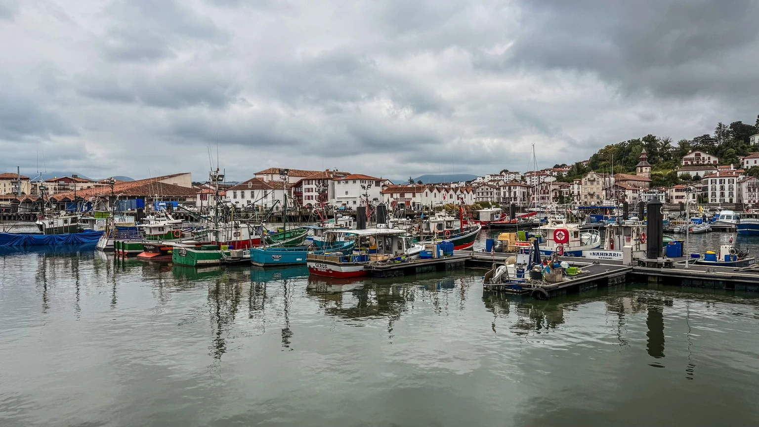 Charming fishing boats docked in the harbor of Saint-Jean-de-Luz on a cloudy day.