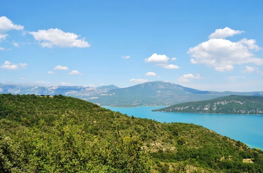 Lac de Sainte-Croix ringed by wooded hills, with mountains in the distance.