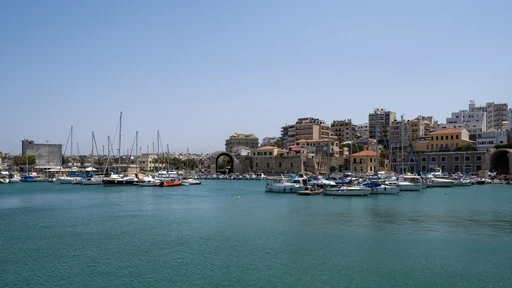 Heraklion harbor with sailboats, the old arsenal arches and the city behind.