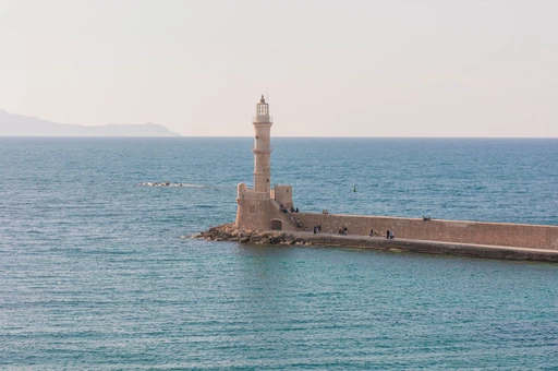 Chania's lighthouse standing in the calm Mediterranean in soft evening light.