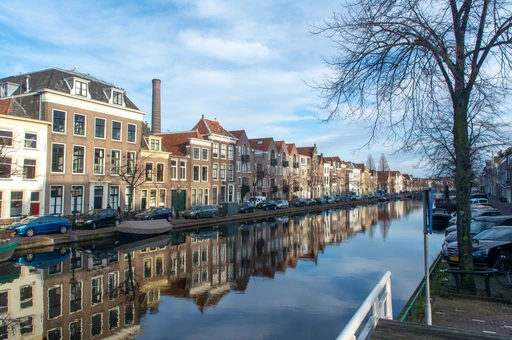 A row of historic Dutch canal houses on a Leiden canal on a bright day.