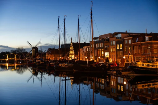 A Leiden canal in the evening light, with moored boats and gabled houses.