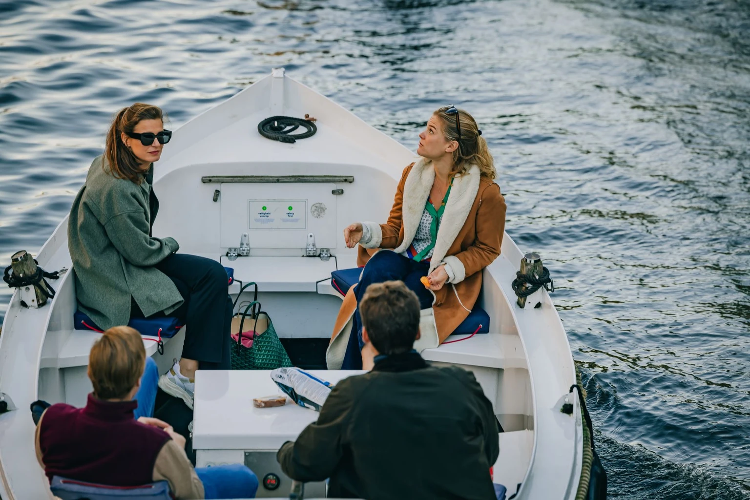 A small open boat with passengers on an Amsterdam canal.