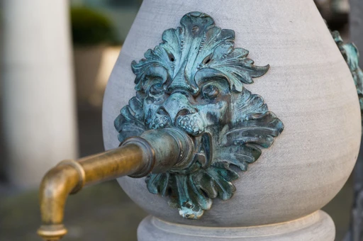 Close-up of a bronze lion-head spout on a stone public drinking fountain in Zurich.