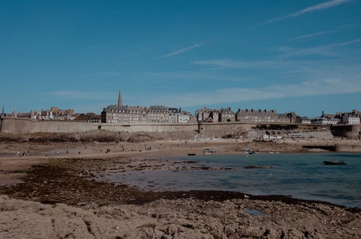 The granite ramparts and tall stone houses of Saint-Malo's walled town above the beach at low tide.