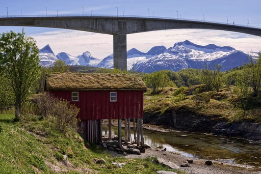 Saltstraumen Bridge and snowy mountain backdrop with cabin in scenic Norway landscape.