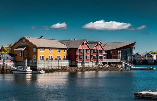 Scenic view of vibrant houses and a calm lake in Svolvær, Nordland, under a clear blue sky.