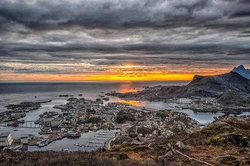 Breathtaking aerial view of Svolvær, Nordland, as the sun sets dramatically over the city and ocean.