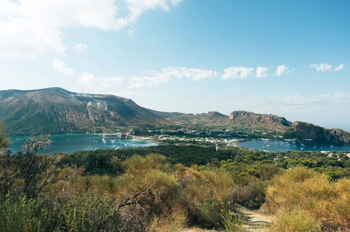The steaming Gran Cratere of Vulcano above the isthmus and its two bays, Porto di Levante and Porto di Ponente, seen from the hillside.