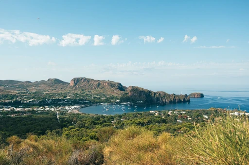 A breathtaking view of a coastal town with a picturesque bay, surrounded by mountains and lush greenery.