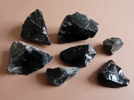 Pieces of black obsidian collected near Monte Pilato on Lipari, their glassy broken faces catching the light.